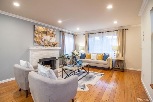 living room with recessed lighting, light wood-style floors, crown molding, baseboards, and a brick fireplace