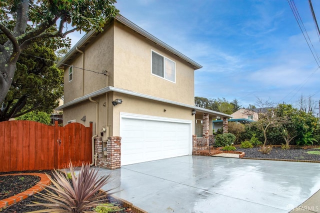 view of home's exterior with stucco siding, brick siding, an attached garage, and fence