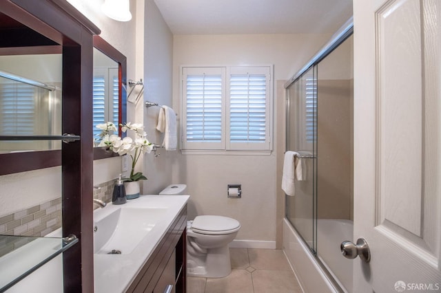 bathroom featuring vanity, baseboards, tile patterned flooring, toilet, and combined bath / shower with glass door