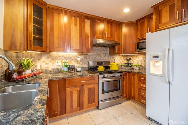 kitchen featuring a sink, brown cabinetry, under cabinet range hood, and stainless steel appliances