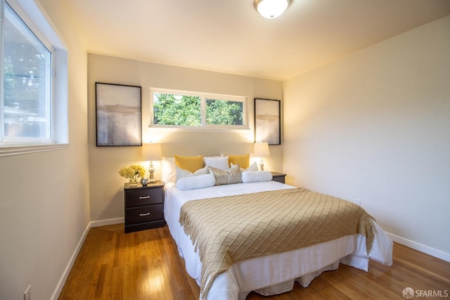 bedroom featuring baseboards, multiple windows, and wood finished floors