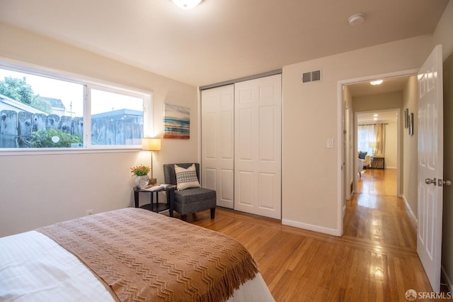 bedroom with a closet, visible vents, baseboards, and light wood-style floors