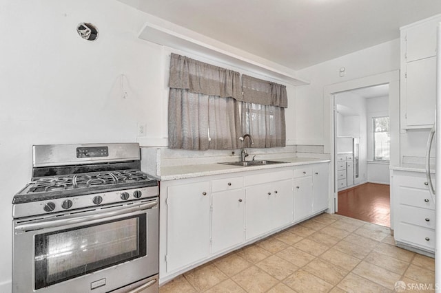 kitchen featuring light hardwood / wood-style floors, white cabinetry, sink, and stainless steel gas range