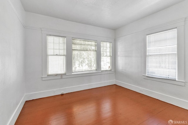 empty room with baseboards and wood finished floors