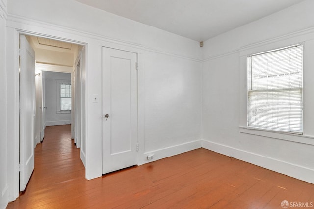 spare room with light wood-type flooring, attic access, and baseboards