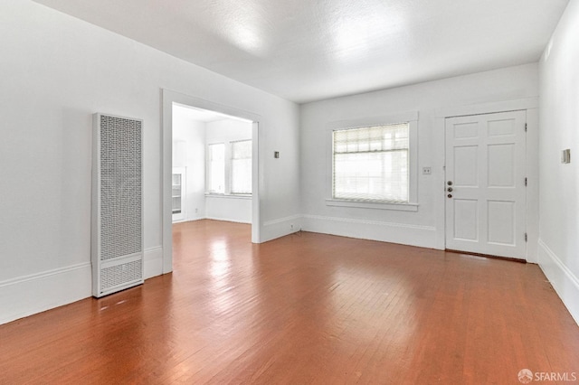 interior space featuring baseboards, a heating unit, and wood finished floors