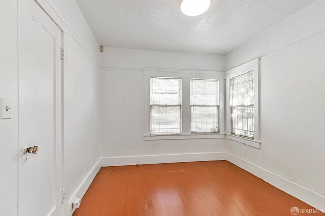 unfurnished room featuring plenty of natural light, light wood-style flooring, and baseboards