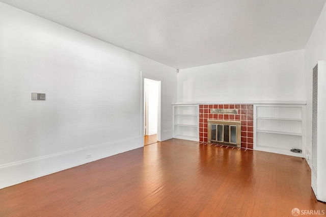 unfurnished living room with hardwood / wood-style flooring and a tile fireplace