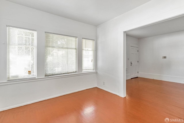 empty room with plenty of natural light and hardwood / wood-style floors