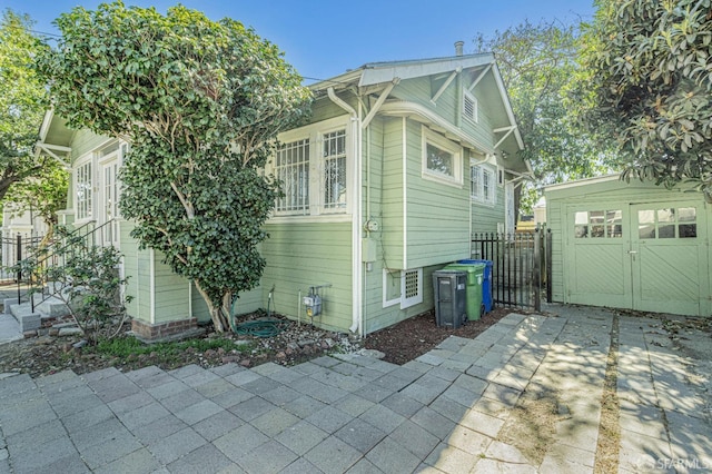 view of property exterior with an outdoor structure, fence, and a patio