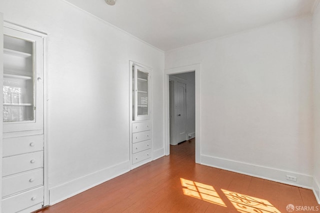 unfurnished bedroom with baseboards, ornamental molding, and wood finished floors