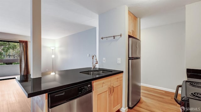 kitchen with light brown cabinetry, sink, light hardwood / wood-style flooring, appliances with stainless steel finishes, and kitchen peninsula