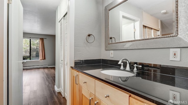 bathroom with hardwood / wood-style flooring, vanity, and a baseboard heating unit