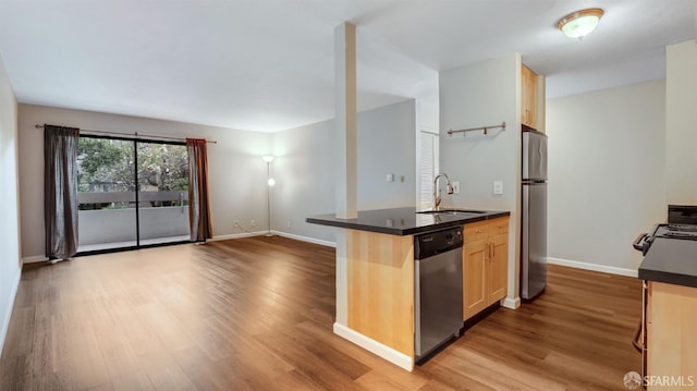 kitchen with appliances with stainless steel finishes, light brown cabinetry, sink, kitchen peninsula, and light hardwood / wood-style flooring