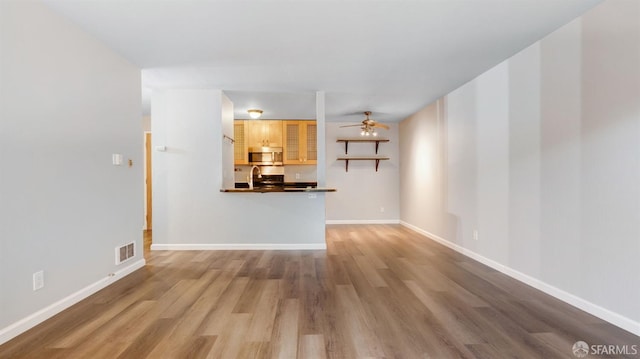 unfurnished living room featuring ceiling fan and hardwood / wood-style floors