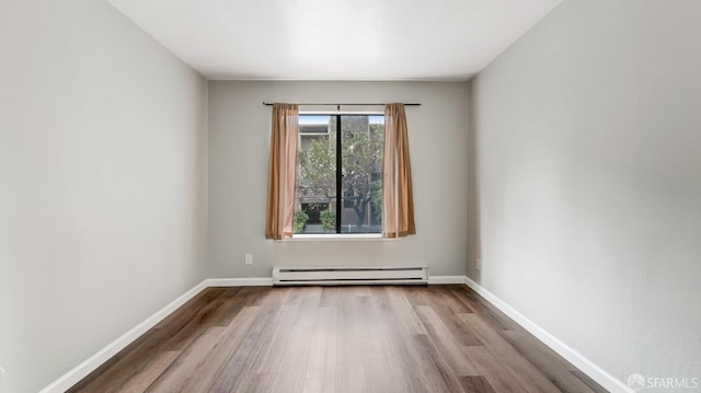 spare room with baseboard heating and light hardwood / wood-style flooring