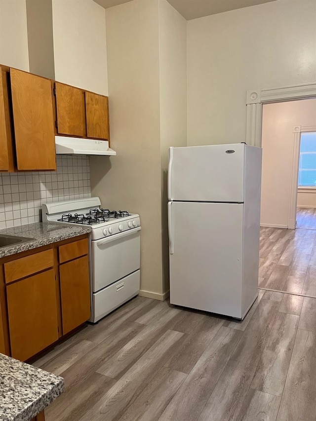 kitchen featuring light wood-type flooring, white appliances, and decorative backsplash