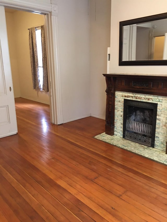 unfurnished living room featuring wood-type flooring and a stone fireplace