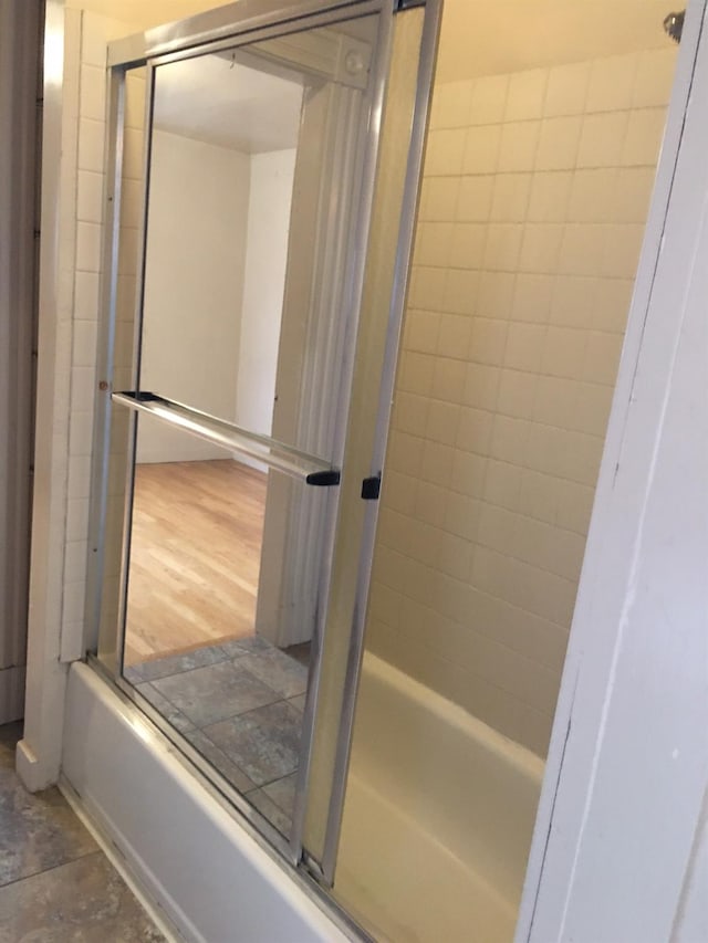 bathroom with bath / shower combo with glass door and wood-type flooring