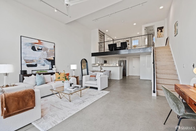 living room with stairway, recessed lighting, a towering ceiling, and finished concrete floors