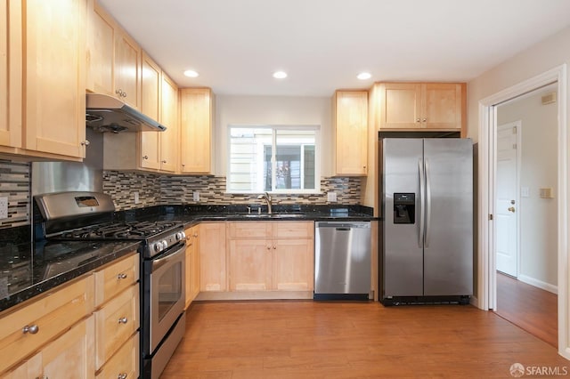 kitchen featuring decorative backsplash, light brown cabinets, light wood-type flooring, and appliances with stainless steel finishes