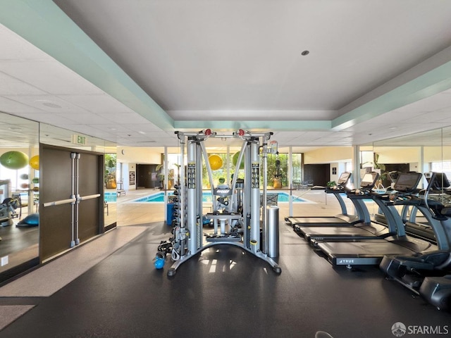 gym featuring a drop ceiling and a wall of windows