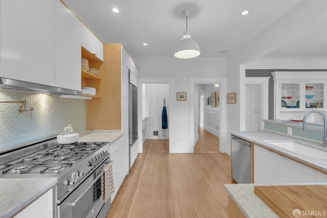 kitchen with a sink, open shelves, white cabinets, appliances with stainless steel finishes, and decorative backsplash
