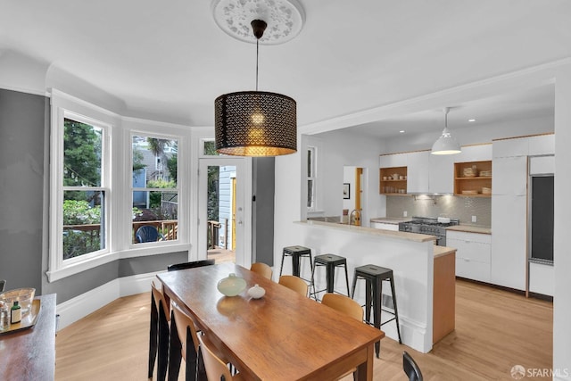 dining area featuring baseboards, light wood-type flooring, and plenty of natural light
