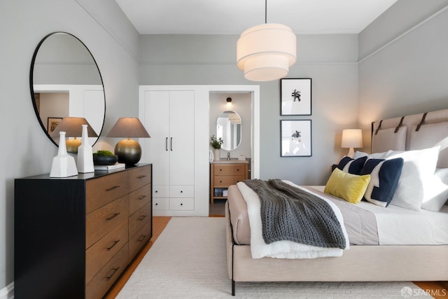 bedroom with ensuite bathroom and light hardwood / wood-style flooring