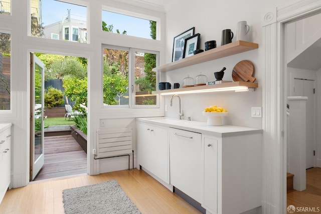 entryway with crown molding, sink, and light wood-type flooring