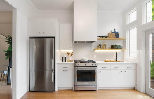 kitchen with tasteful backsplash, ornamental molding, stainless steel appliances, light hardwood / wood-style floors, and white cabinets