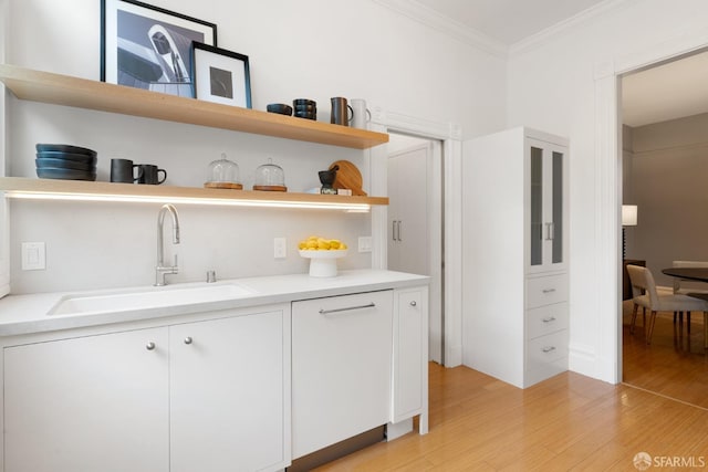 bar featuring white cabinetry, sink, and ornamental molding