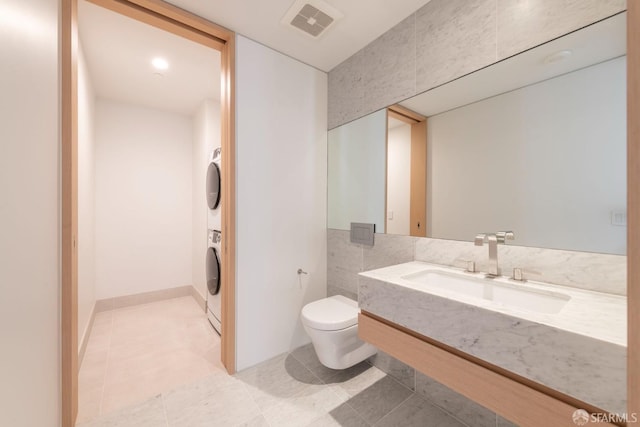 bathroom with toilet, vanity, and stacked washer and dryer