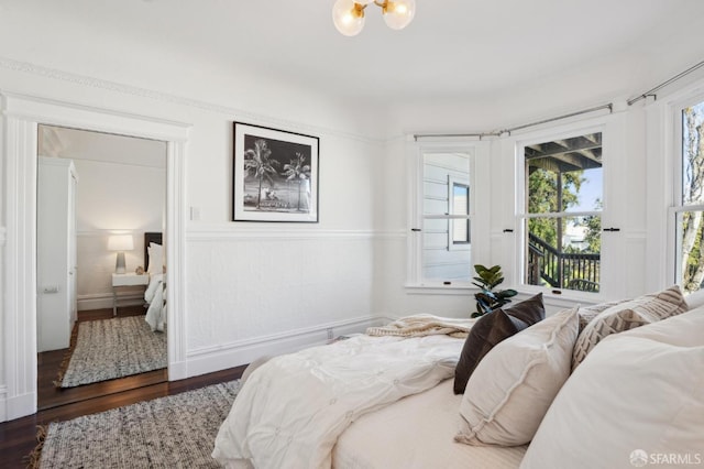 bedroom featuring ensuite bathroom, dark wood finished floors, and access to exterior