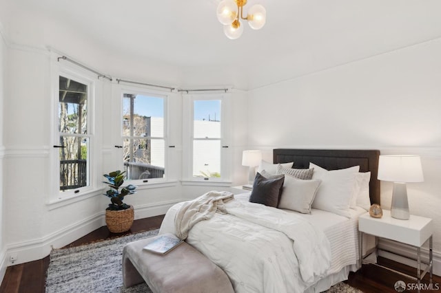 bedroom with dark wood-style floors, baseboards, and a notable chandelier