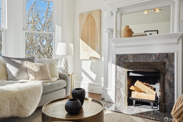 living area featuring a tile fireplace and ornate columns