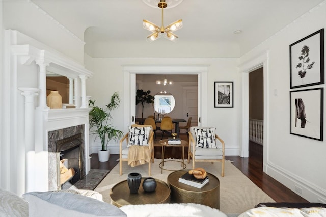 living room with baseboards, dark wood-type flooring, a fireplace, and a notable chandelier