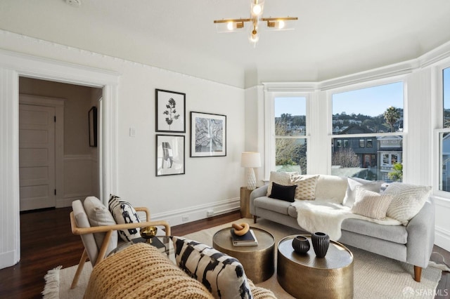 living room with an inviting chandelier, baseboards, and dark wood-type flooring