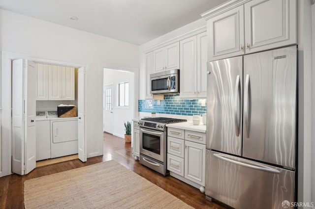 kitchen featuring decorative backsplash, appliances with stainless steel finishes, light countertops, washing machine and dryer, and white cabinetry