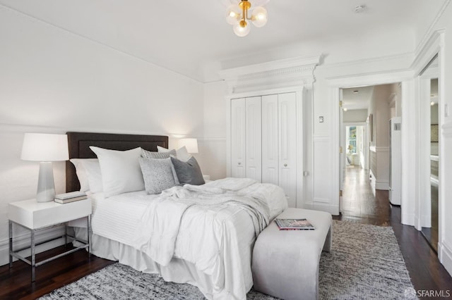 bedroom with a notable chandelier, dark wood-style flooring, and a closet