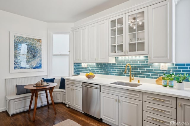 kitchen with glass insert cabinets, light countertops, dishwasher, and a sink