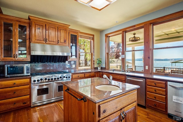 kitchen featuring a kitchen island with sink, sink, stainless steel appliances, and a water view