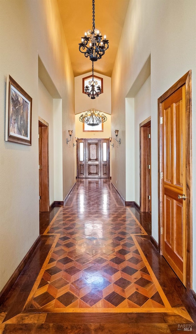 corridor featuring an inviting chandelier, dark parquet floors, and high vaulted ceiling