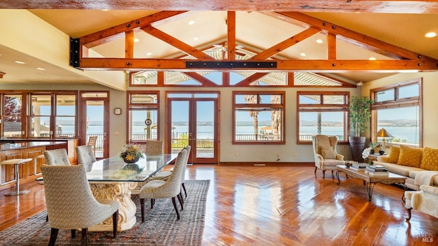 dining space featuring a water view, light wood-type flooring, high vaulted ceiling, and french doors