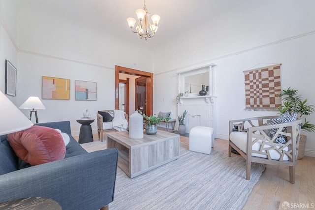 living area featuring baseboards, a notable chandelier, and light wood finished floors