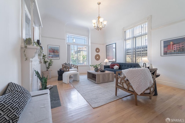 living room featuring a notable chandelier, baseboards, and wood finished floors