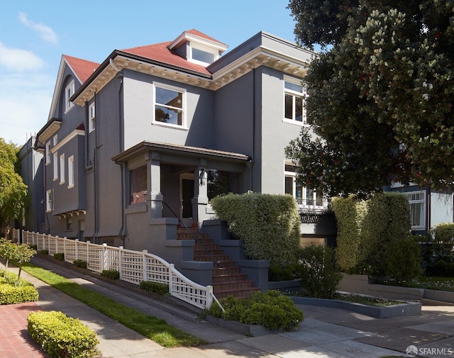 view of front of house featuring stairway, fence, and stucco siding
