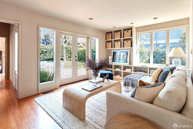 living area featuring recessed lighting, visible vents, french doors, and light wood finished floors