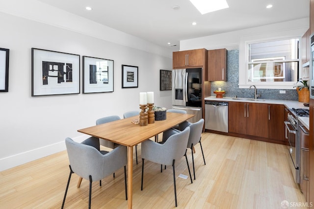 kitchen featuring a sink, backsplash, recessed lighting, stainless steel appliances, and a skylight