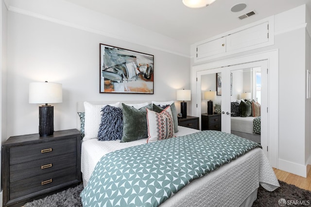 bedroom featuring visible vents, baseboards, french doors, wood finished floors, and a closet